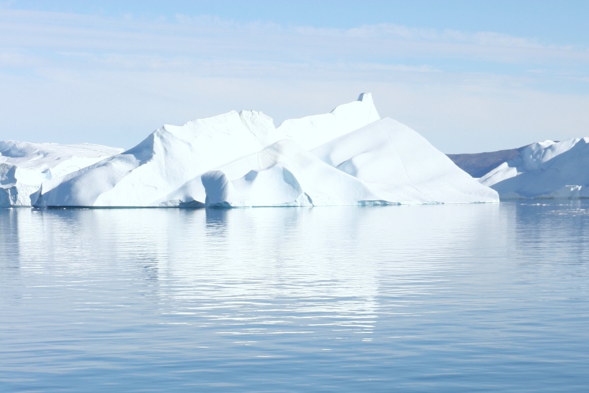 A sculpted iceberg floating in calm blue water